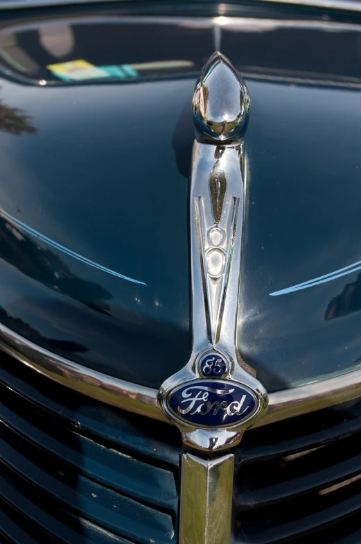 a shiny chrome hood ornament on the front of a ford automobile