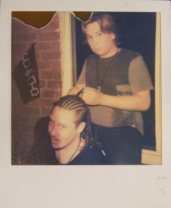an old polaroid picture shows a young man  another mans hair