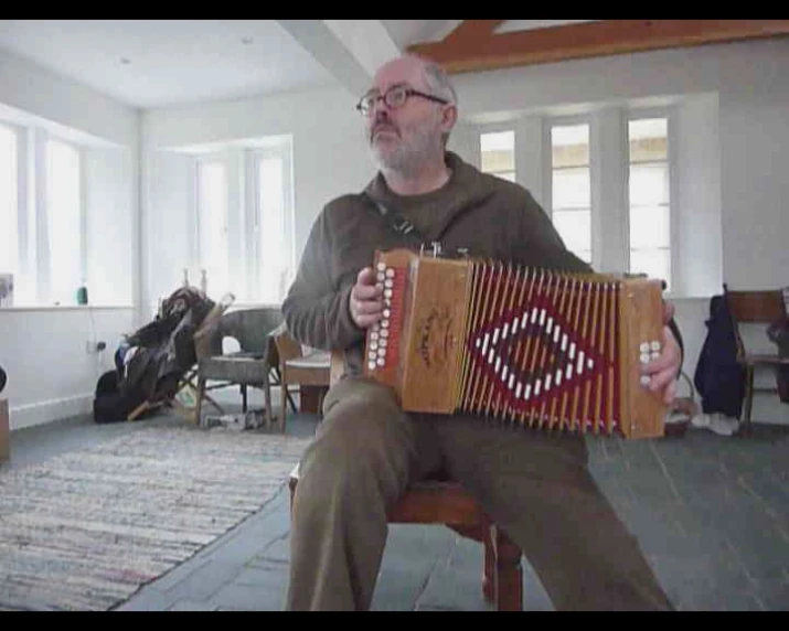 an old man sitting down holding a very large piece of music