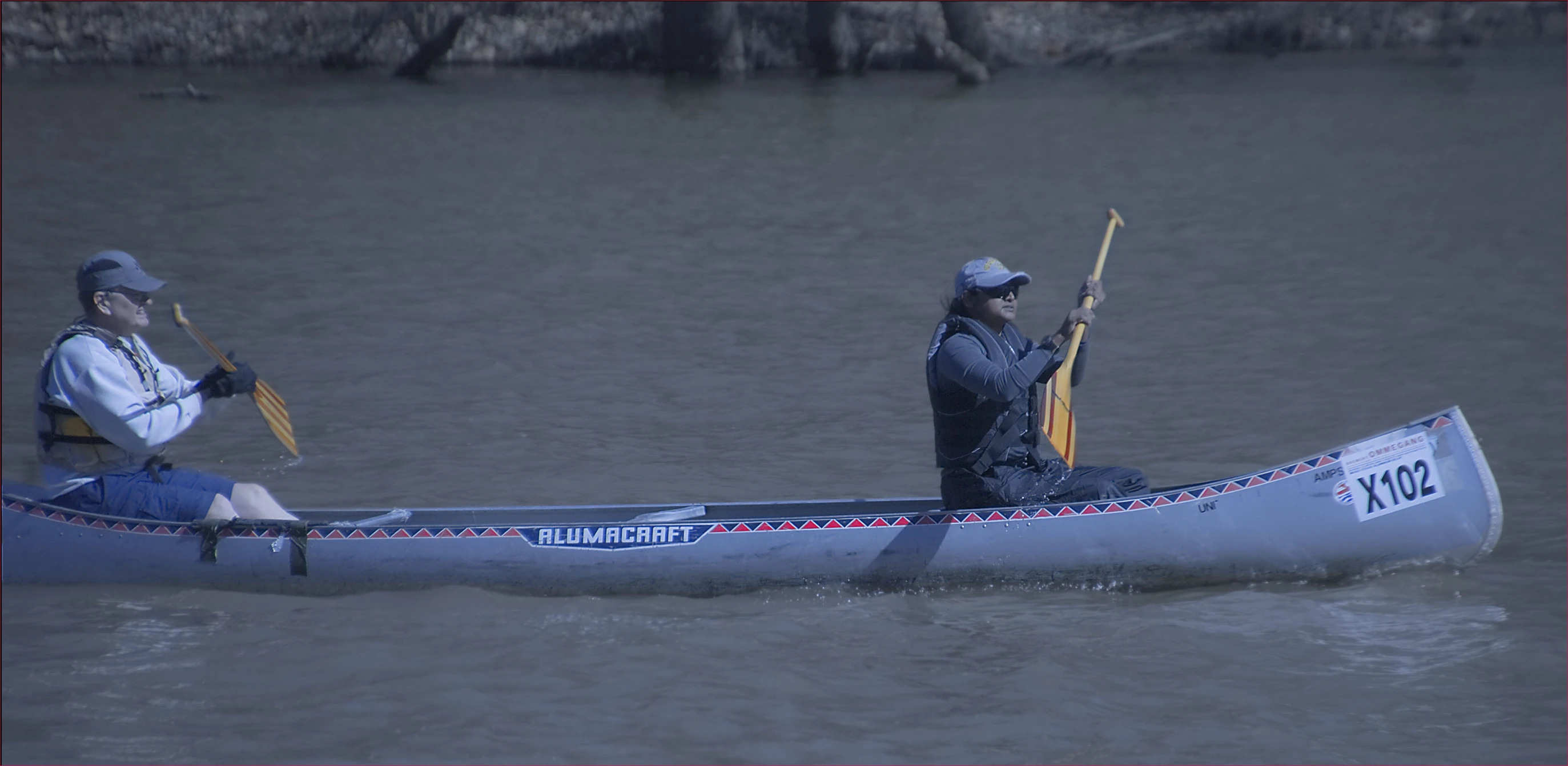 two people in a canoe with paddles on the water