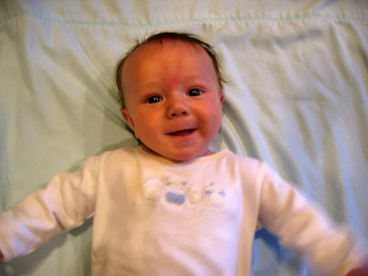 the young baby lies in his white outfit