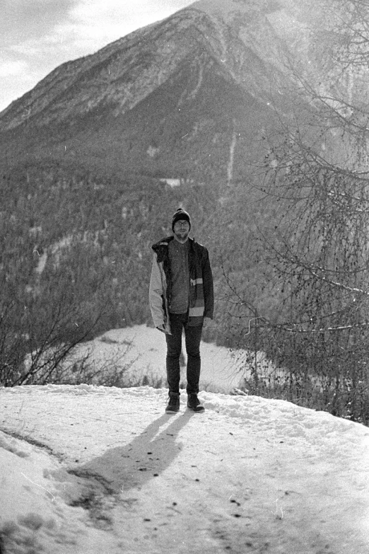 a man stands on a snowy hill with his snowboard