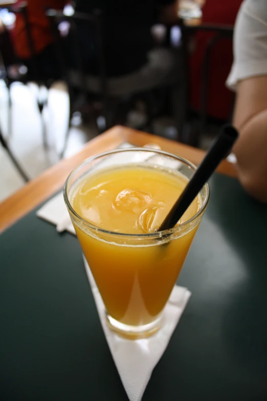 an orange drink with straw sitting on top of a table