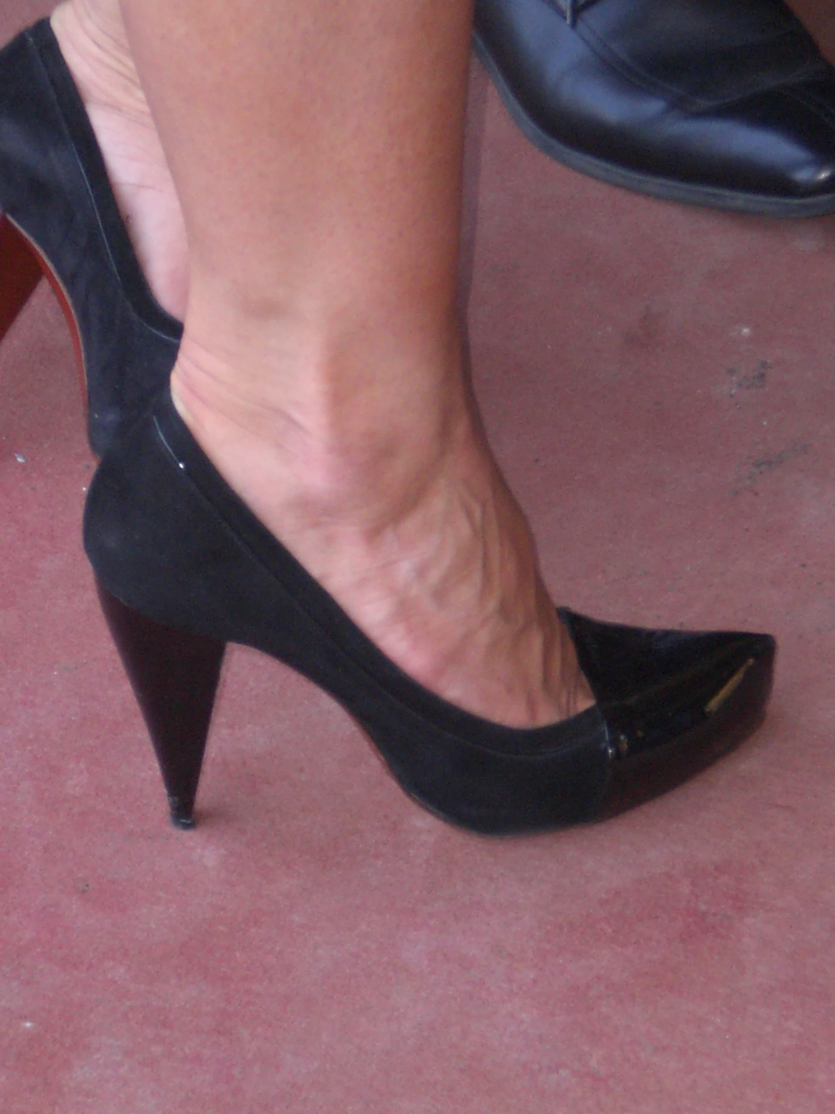 a women is wearing black pumps with a black strap and heels