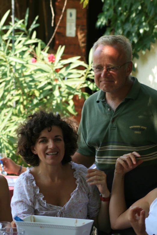 a man is getting ready to eat at a table while two women look on