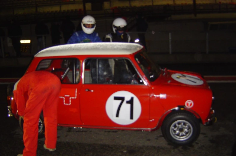 two men in costumes work on a red mini car