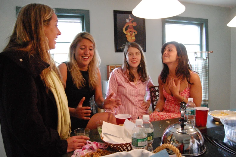 four girls standing around a counter with one holding a glass and smiling