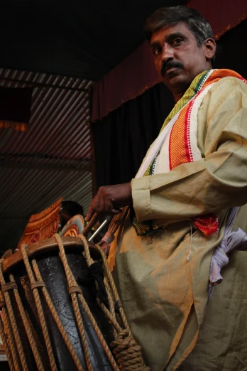 a man in an orange and yellow outfit holds a drum