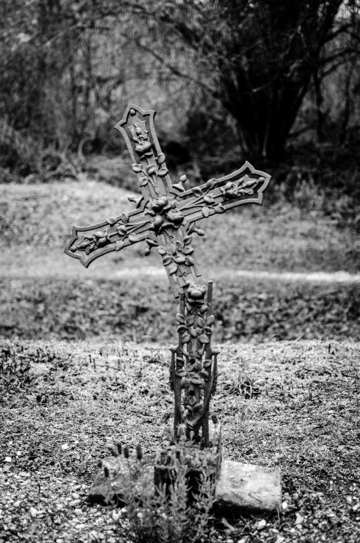 a wooden cross stands in front of a pile of dead leaves