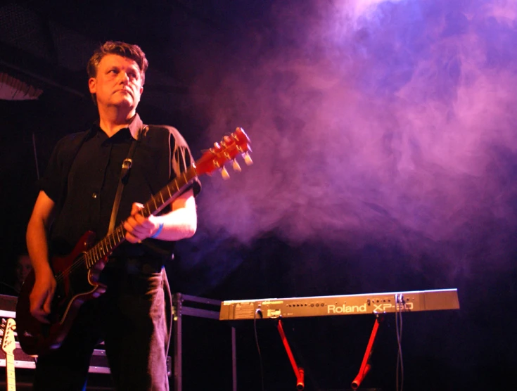 a young man holding a guitar at night