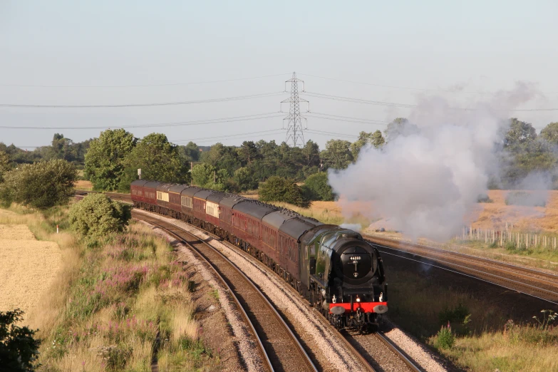 a black train engine traveling down tracks near trees