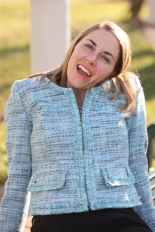 a woman smiles brightly while sitting on a bench