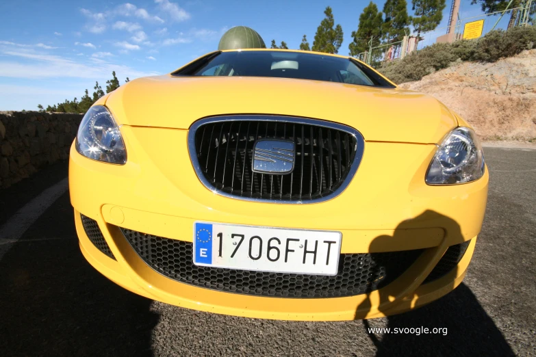 a yellow sport car parked on a gravel lot