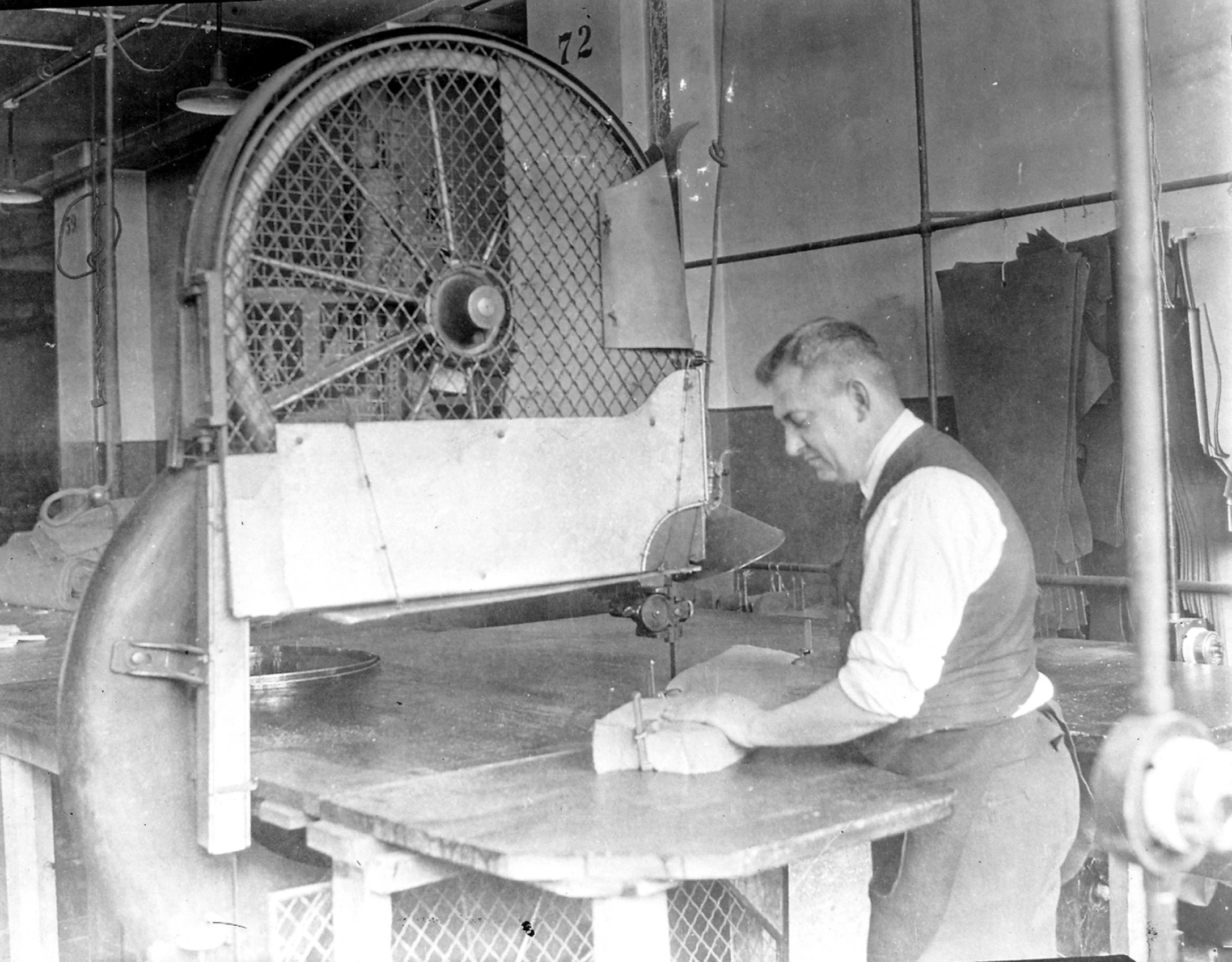 man in apron and apron shirt using a machine to spin a sheet of paper