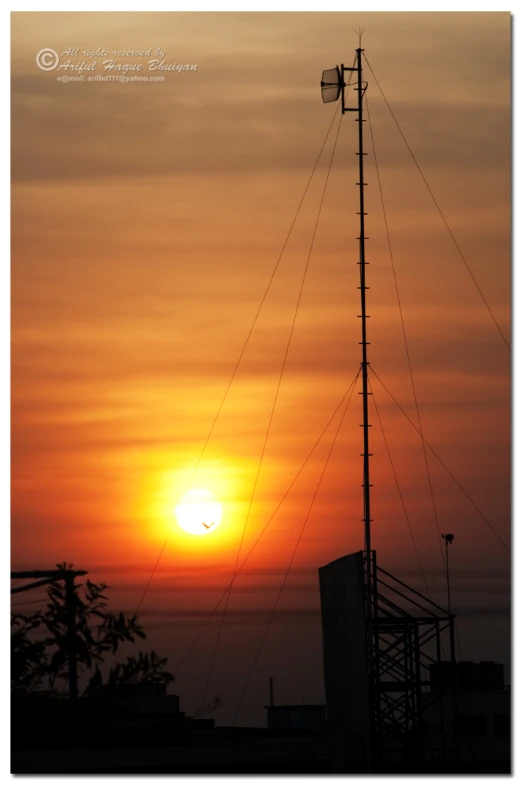 a very tall pole with the sun setting in background