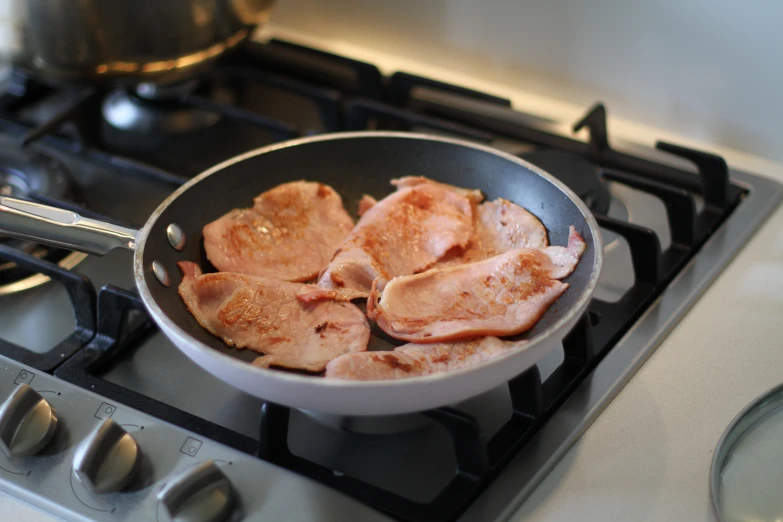 raw meat being cooked in a frying pan on top of the stove