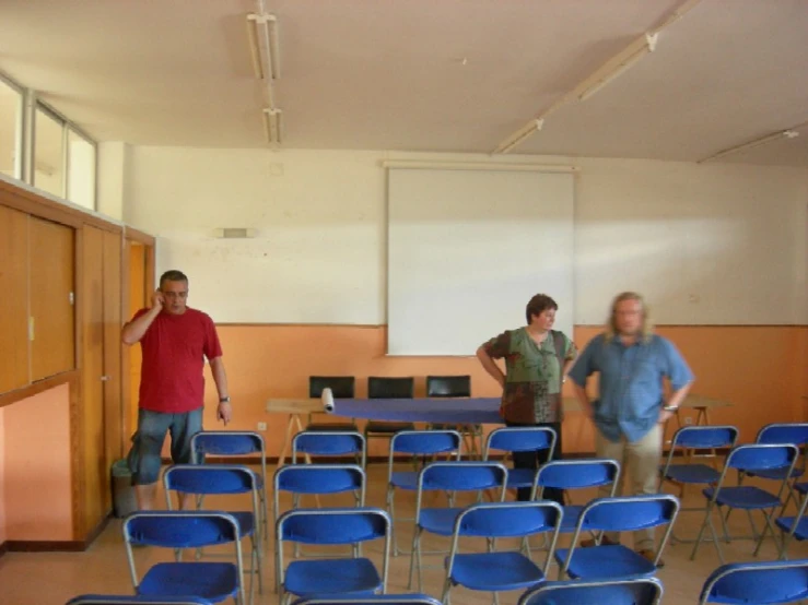a group of people in a room with blue chairs