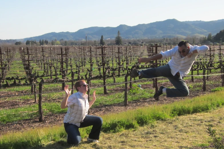 two men in the air near a vines in an orchard