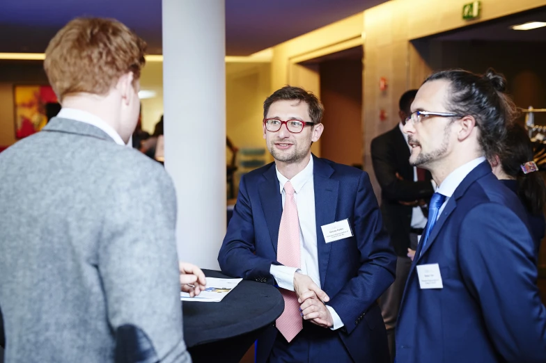 two men in suits talking with one another at an event