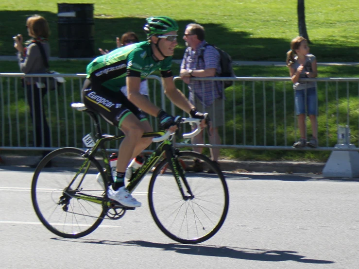 the man in the green shirt is riding his bicycle down the street