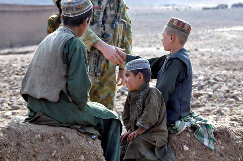 there are three children that are sitting on a rock