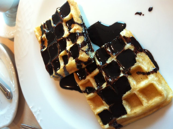 a plate topped with two waffles covered in syrup