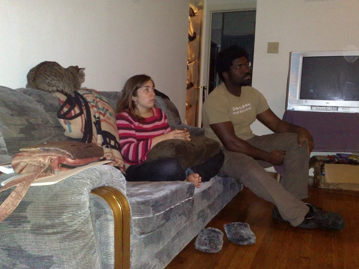 man and woman sitting on couch with wooden floor