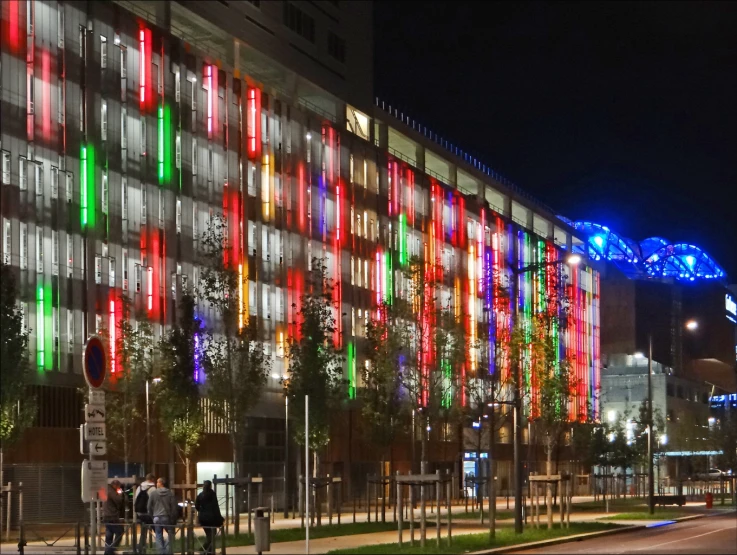 people are standing outside a brightly lit building at night