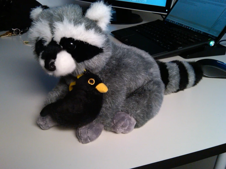 a stuffed animal sitting on a desk in front of a laptop