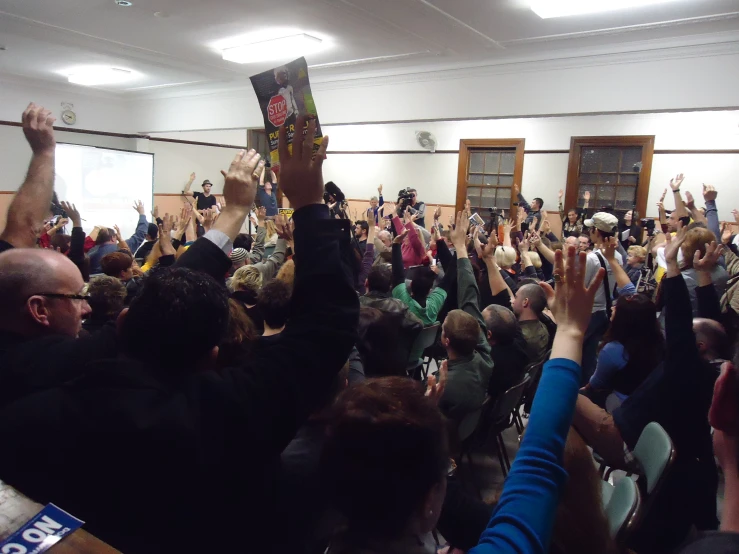 a crowd of people raising their hands in a room