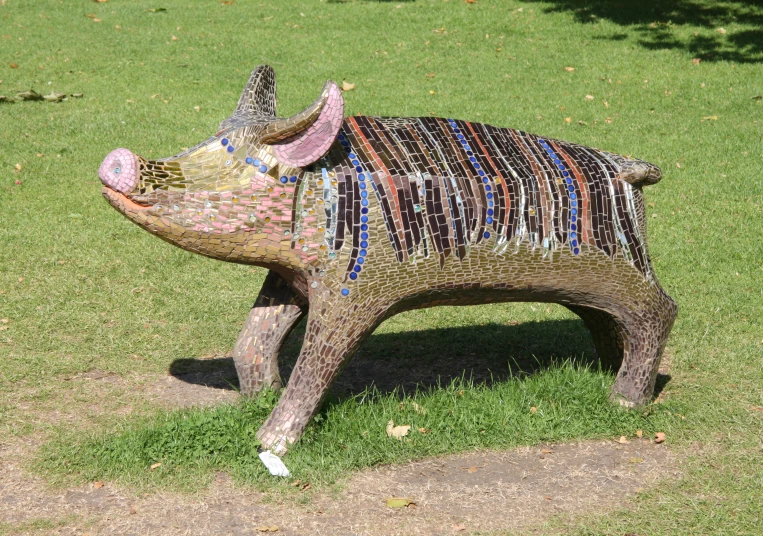 a mosaicated pig sculpture is in the grass