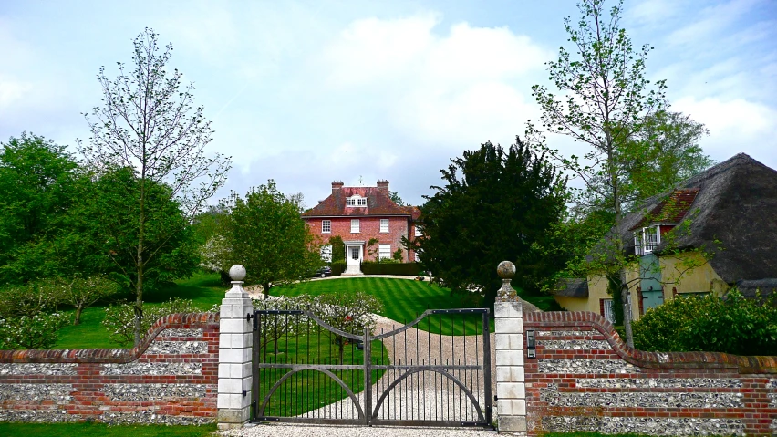 a gate and house with trees behind it