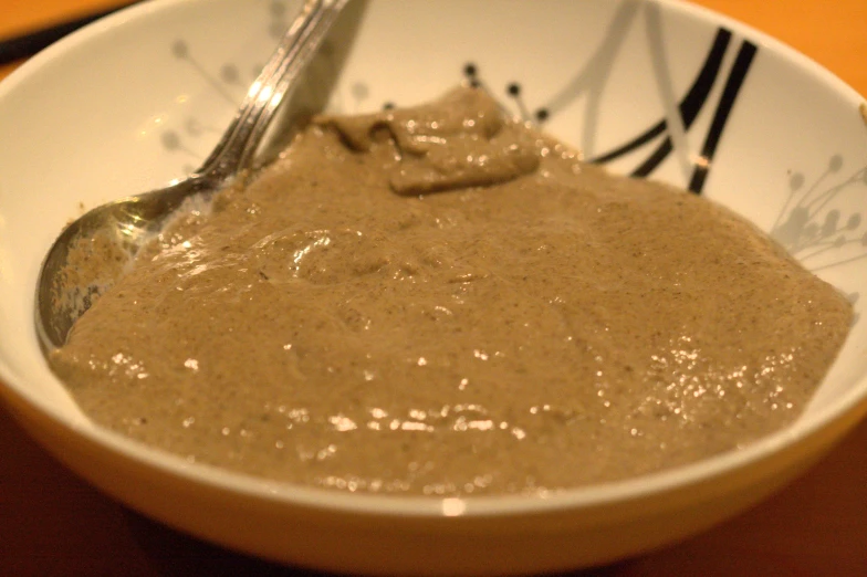 a white bowl with oatmeal and chocolate sitting on a table