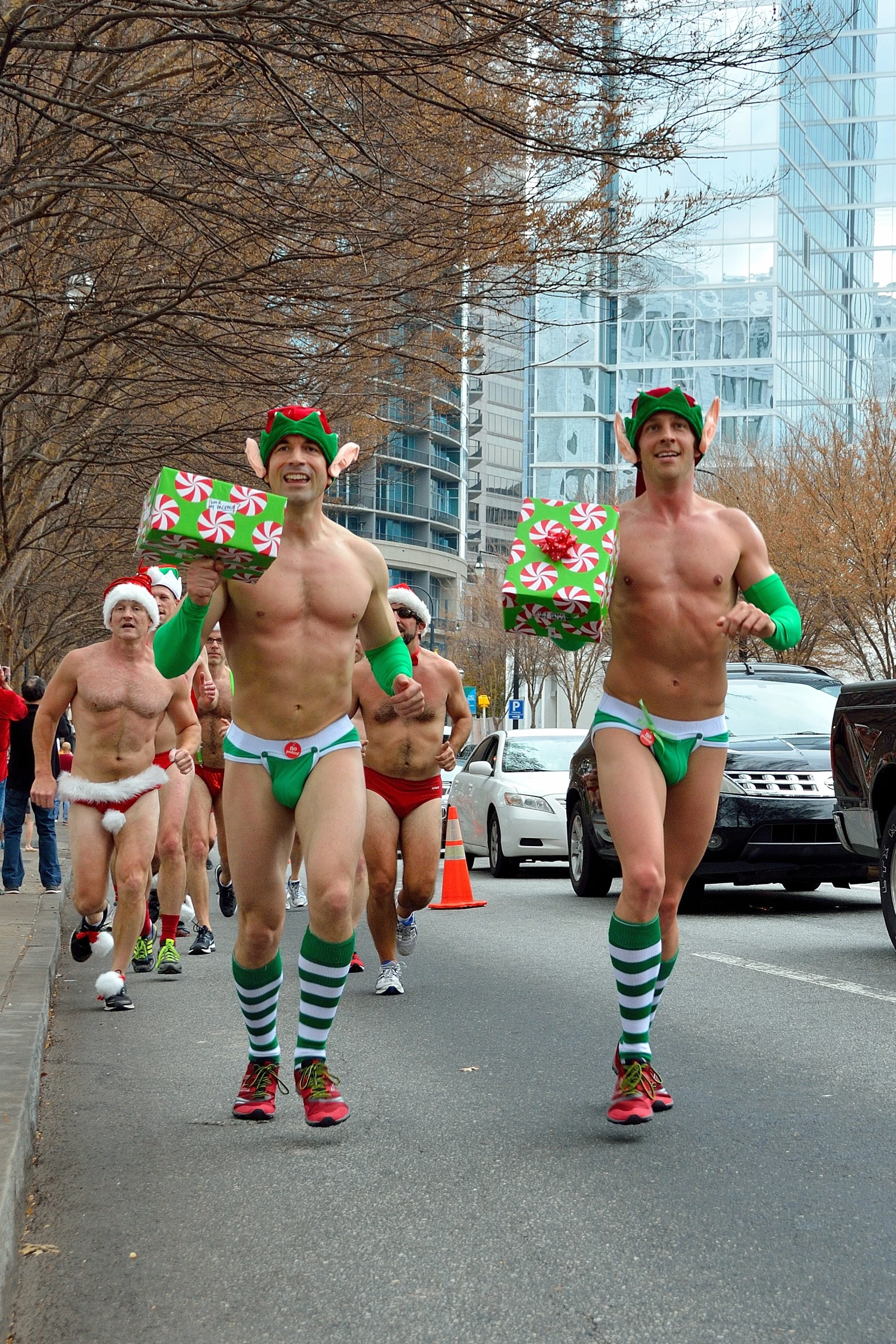 several men in green and white underwear running in a parade