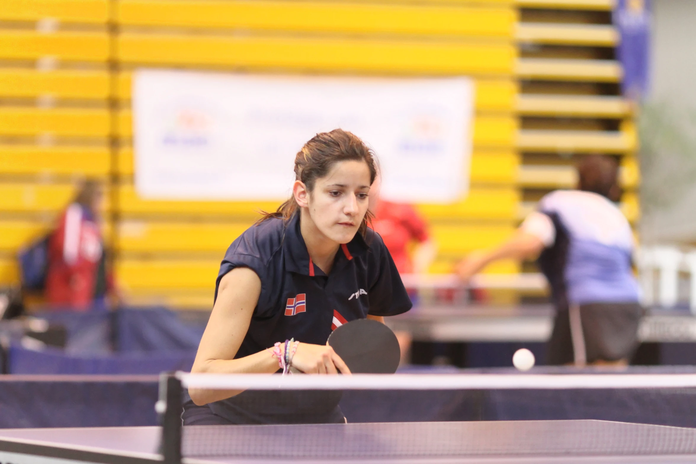 a girl is looking down at the ball as she prepares to serve