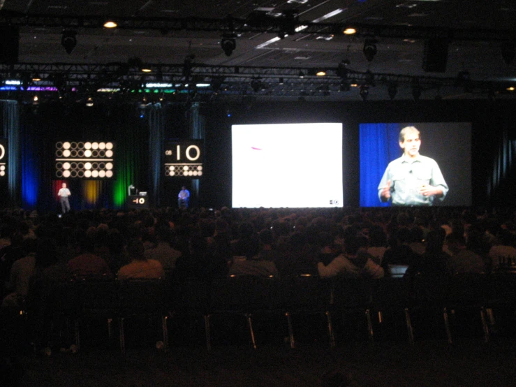 a crowd in a dark room next to large screens