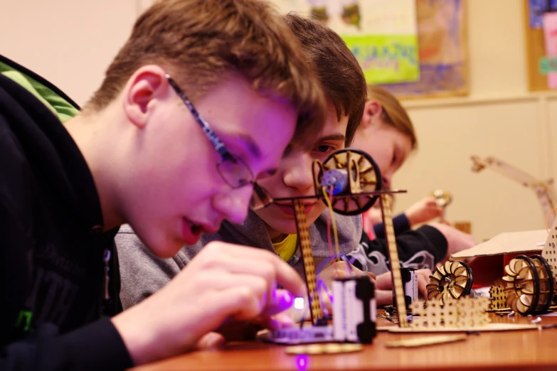 young men playing with miniature model structures on table