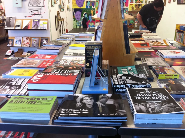 a man sitting on top of a blue shelf next to a pile of books