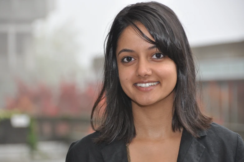 a close up of a person smiling with a building in the background