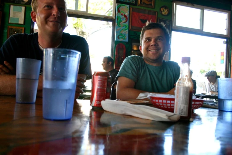 two men sitting at a bar with empty glasses