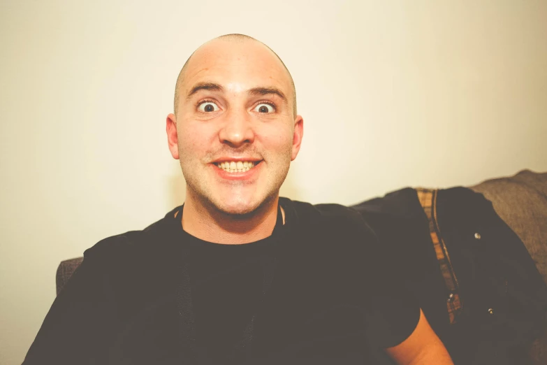 a bald headed man making a face and smiling