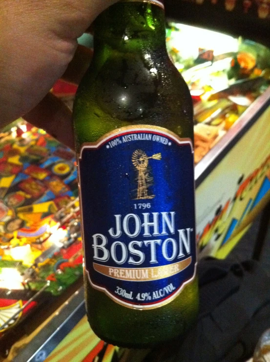 a person holding up a beer at a pin bowling game