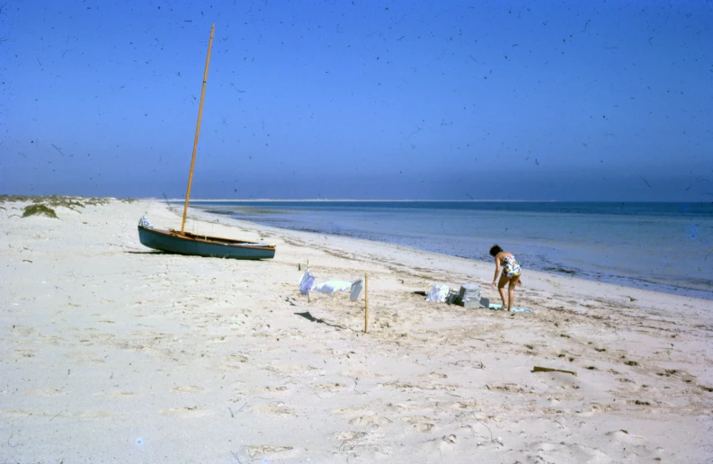 a person on the beach and a boat in the water