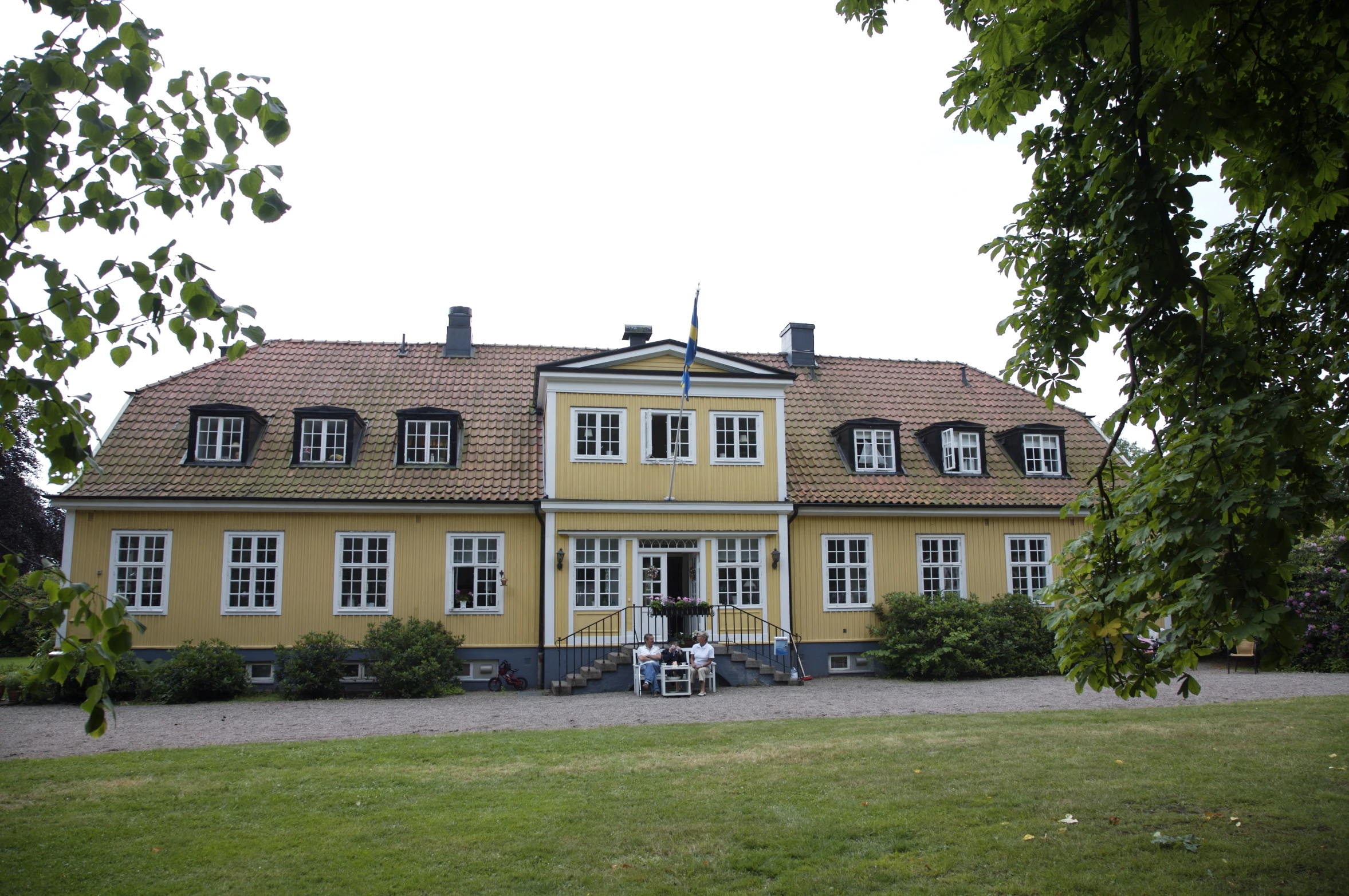 a big house with lots of windows, bushes and trees