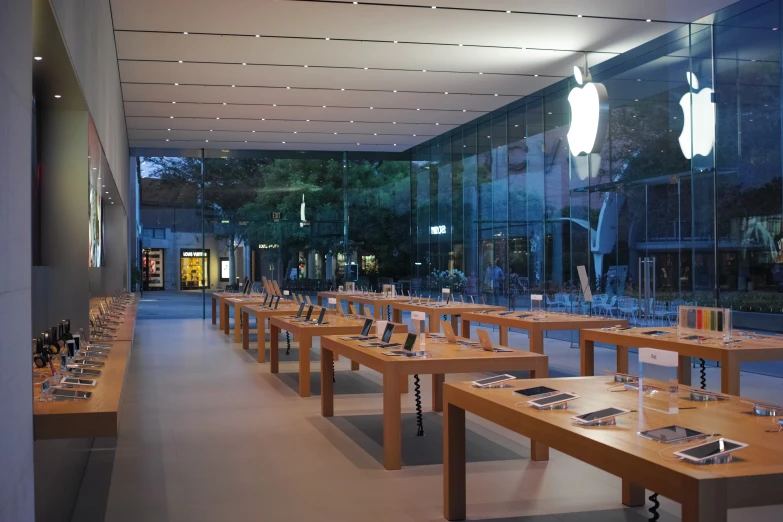 a line of wooden tables sit in the middle of a building