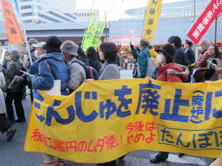 an asian crowd is protesting with a banner
