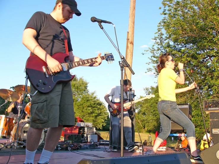 two people singing while playing guitar next to a man and woman playing a trumpet