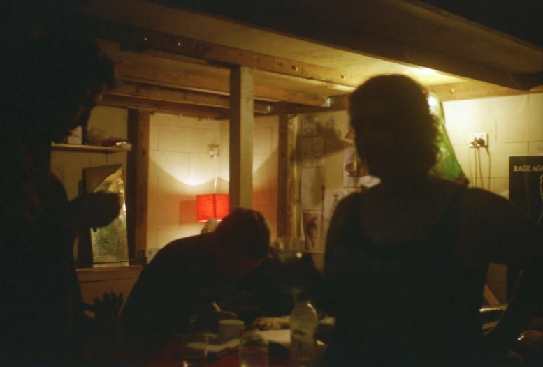 three people in a dimly lit kitchen with a table