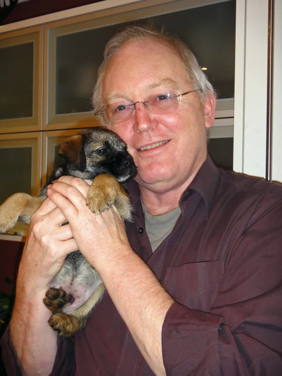 a man holding a small dog in his right hand