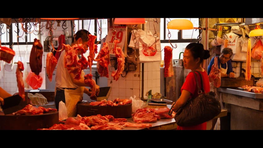 a man and woman looking at various meat hanging